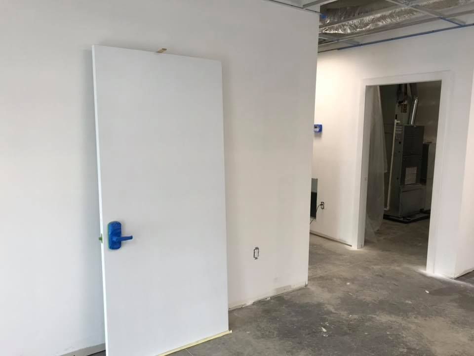 An empty room with a white door and a blue handle.