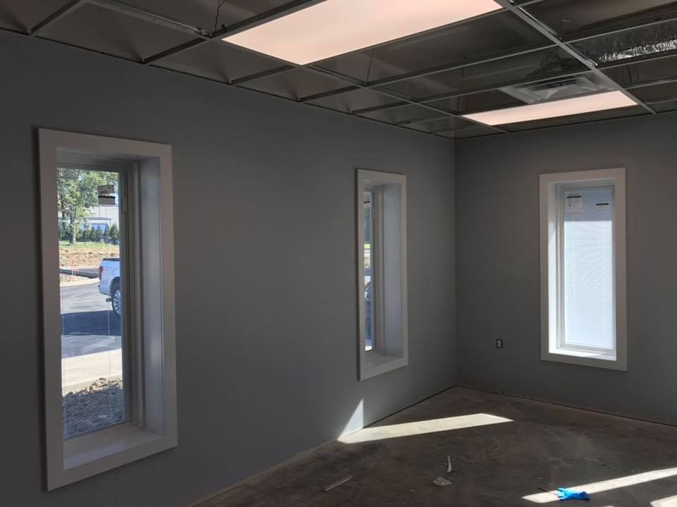 A room with a lot of windows and a car parked in the background