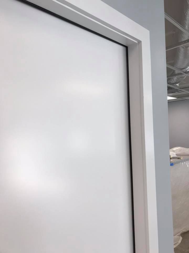 A close up of a white door with a black frame in a room.