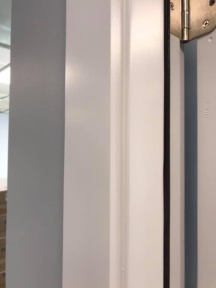 A close up of a door hinge on a white door.