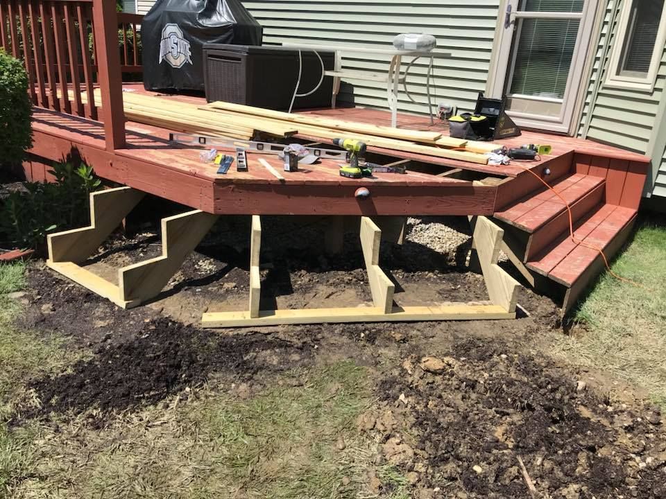 A wooden deck is being built in the backyard of a house.