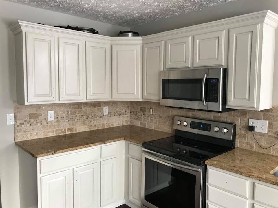 A kitchen with white cabinets , stainless steel appliances , and granite counter tops.