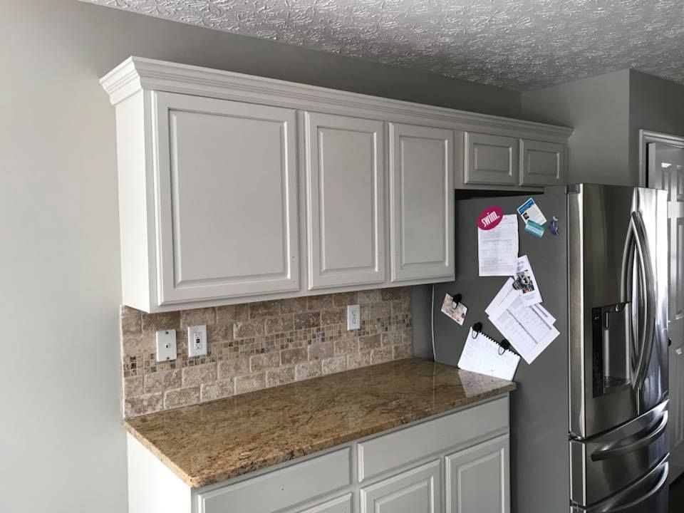A kitchen with white cabinets and a stainless steel refrigerator.