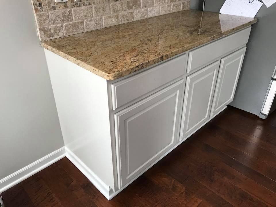 A kitchen with white cabinets and a granite counter top.