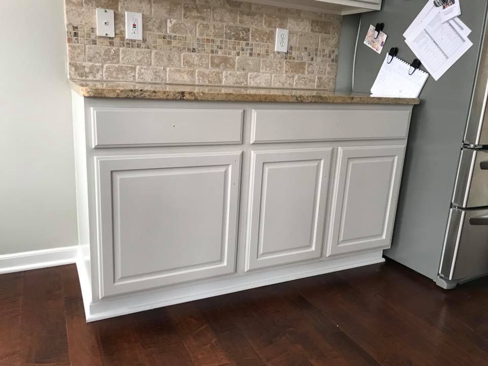 A kitchen with white cabinets and a stainless steel refrigerator.