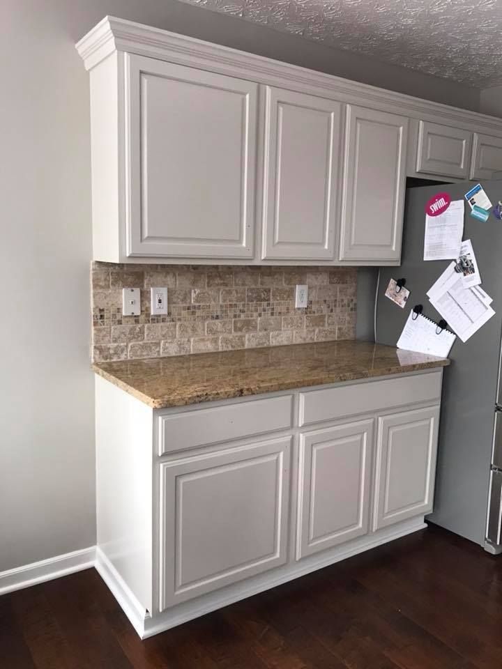 A kitchen with white cabinets , granite counter tops , and a refrigerator.