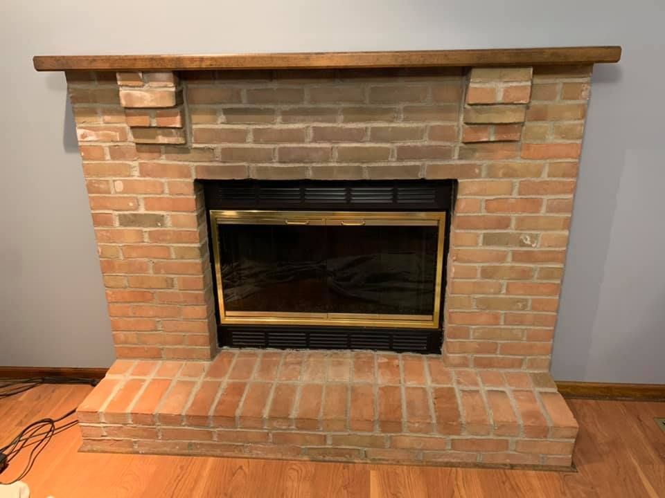 A brick fireplace with a wooden mantle in a living room.