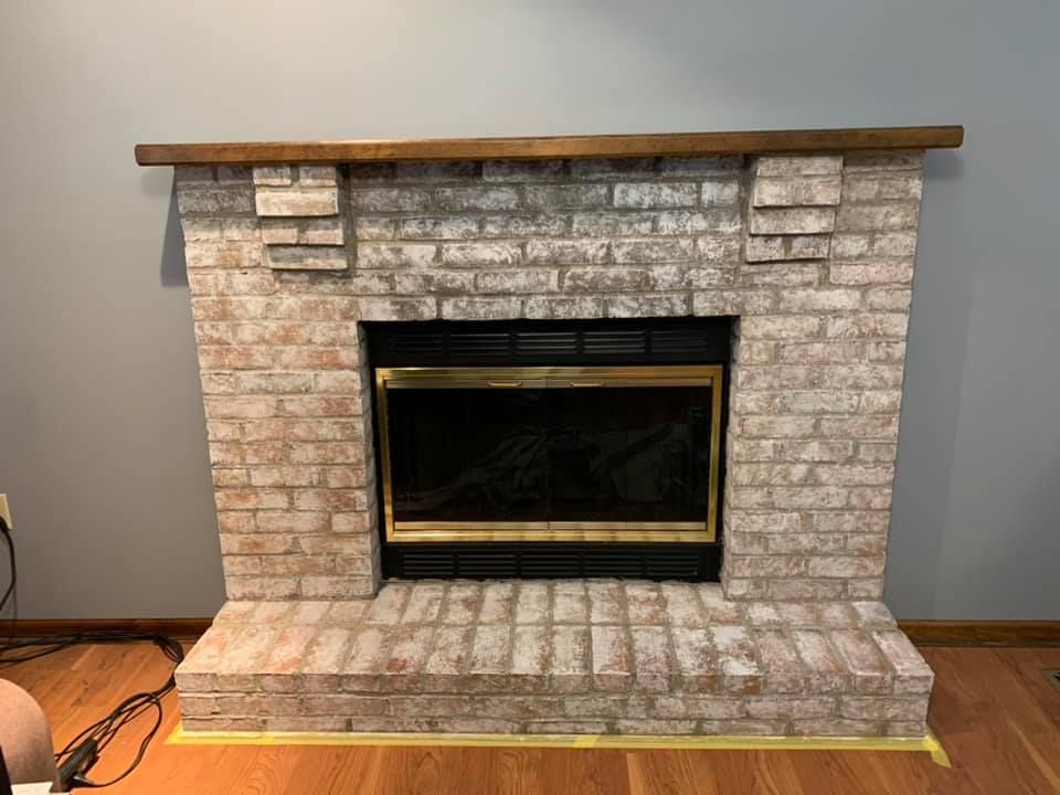 A brick fireplace with a wooden mantle in a living room.