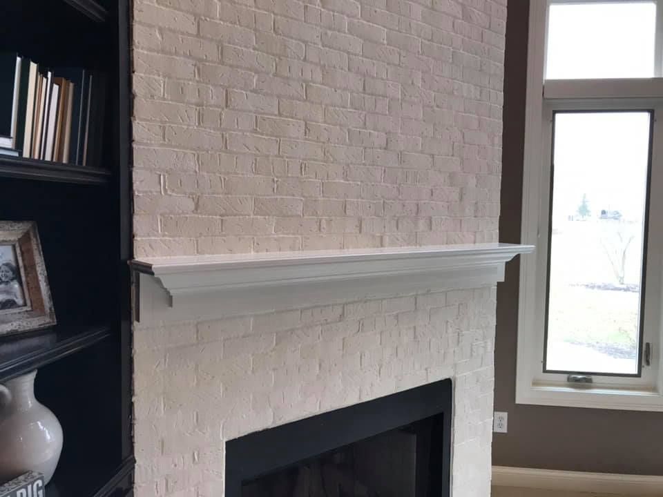 A living room with a fireplace , bookshelf , and window.