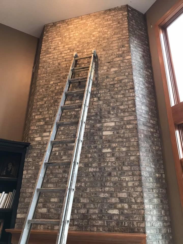 A ladder is leaning against a brick wall in a living room.