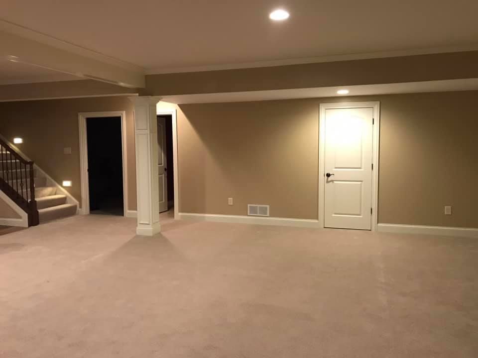 An empty basement with a staircase and a door.