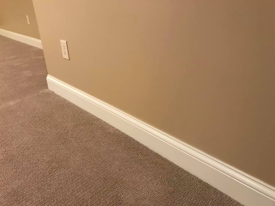A room with a carpeted floor and a wall with white trim.