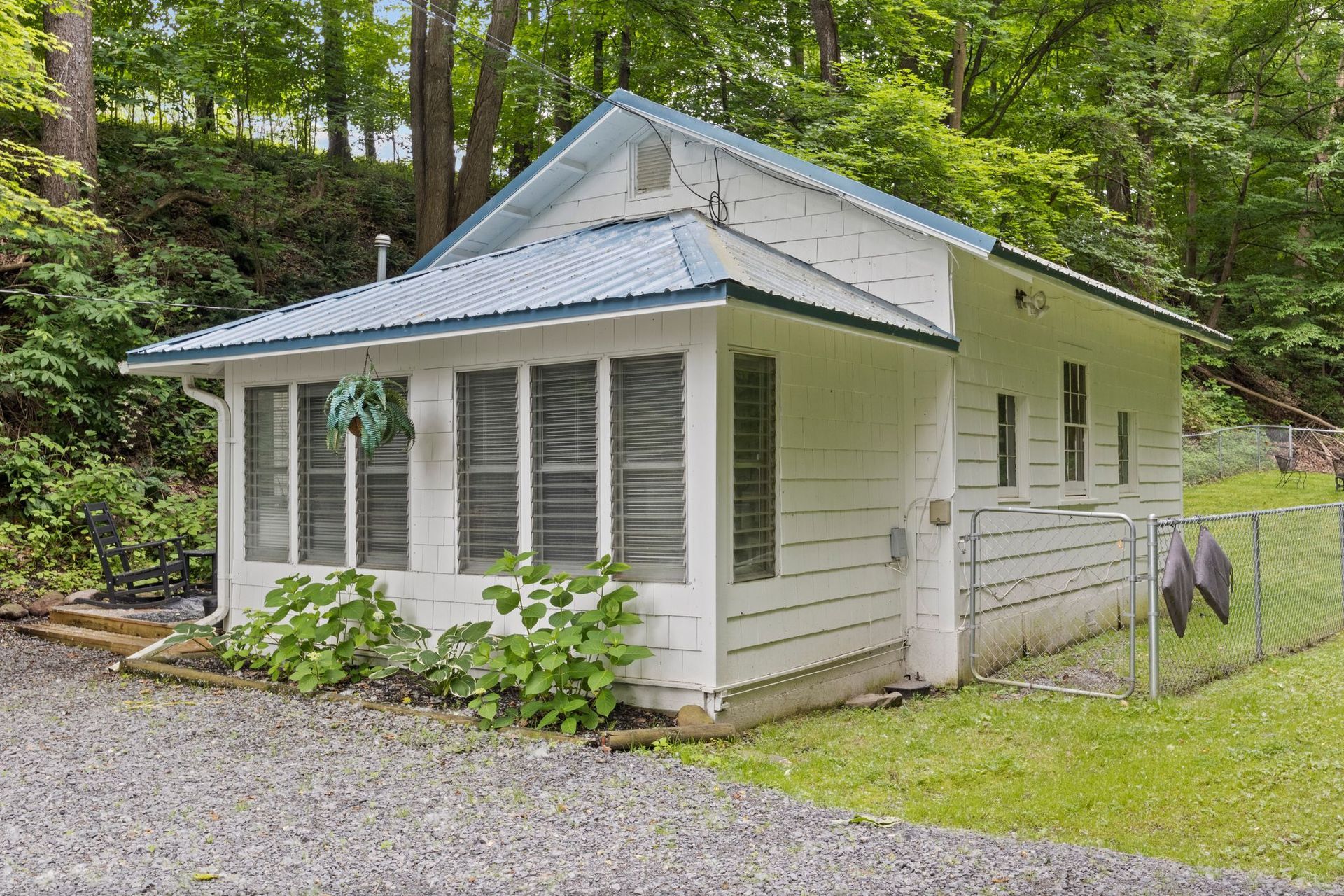 Sunlit view from inside a room with wooden frame, overlooking a yard with plants.