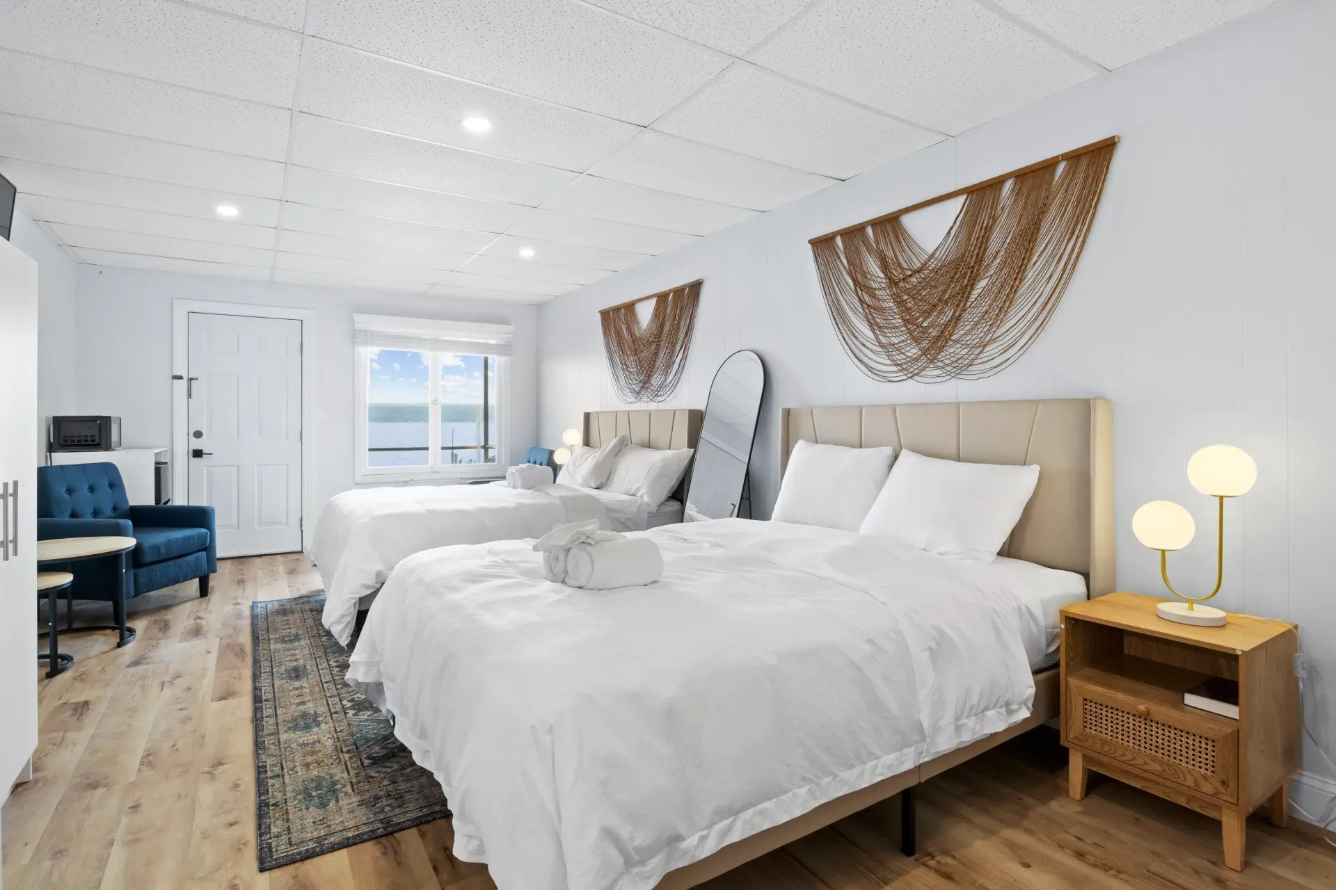 Hotel room with two beds, white bedding, floral runner, large window with view.