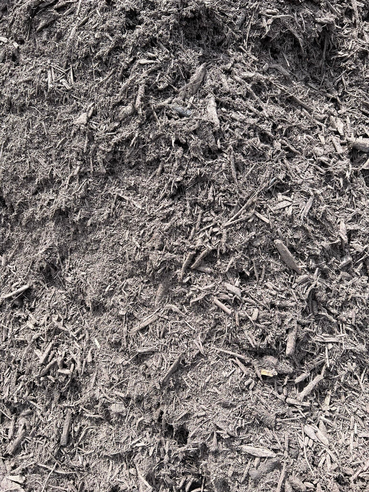 Pile of dark wood mulch, textured with varying sizes of wood chips.