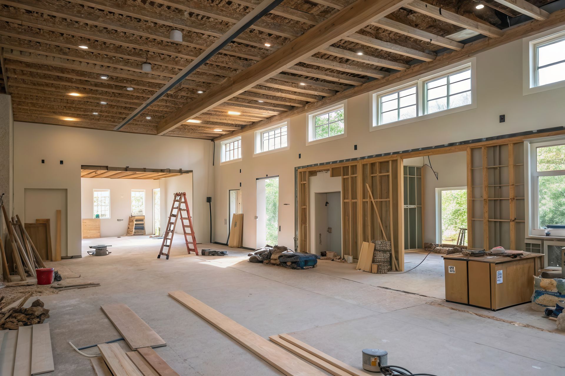 Interior of a building under construction, showing exposed wooden beams, studs, and unfinished floors.