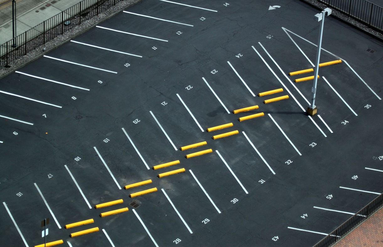 Aerial view of an empty parking lot with yellow zigzag lane markings and white parking spaces. Aerial view of an empty parking lot with yellow zigzag lane markings and white parking spaces.