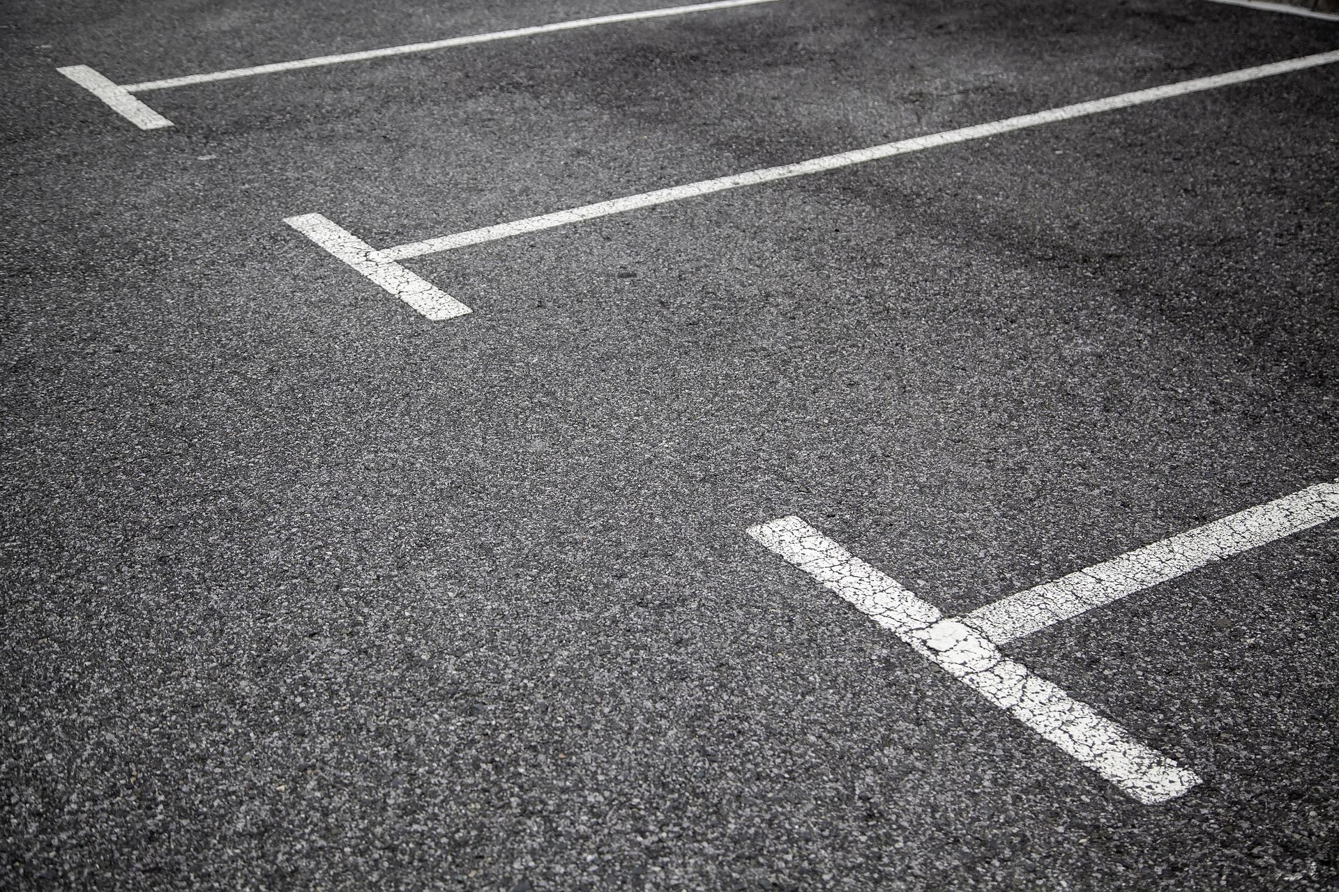 Empty parking lot with white painted parking space lines on dark asphalt. Empty parking lot with white painted parking space lines on dark asphalt.