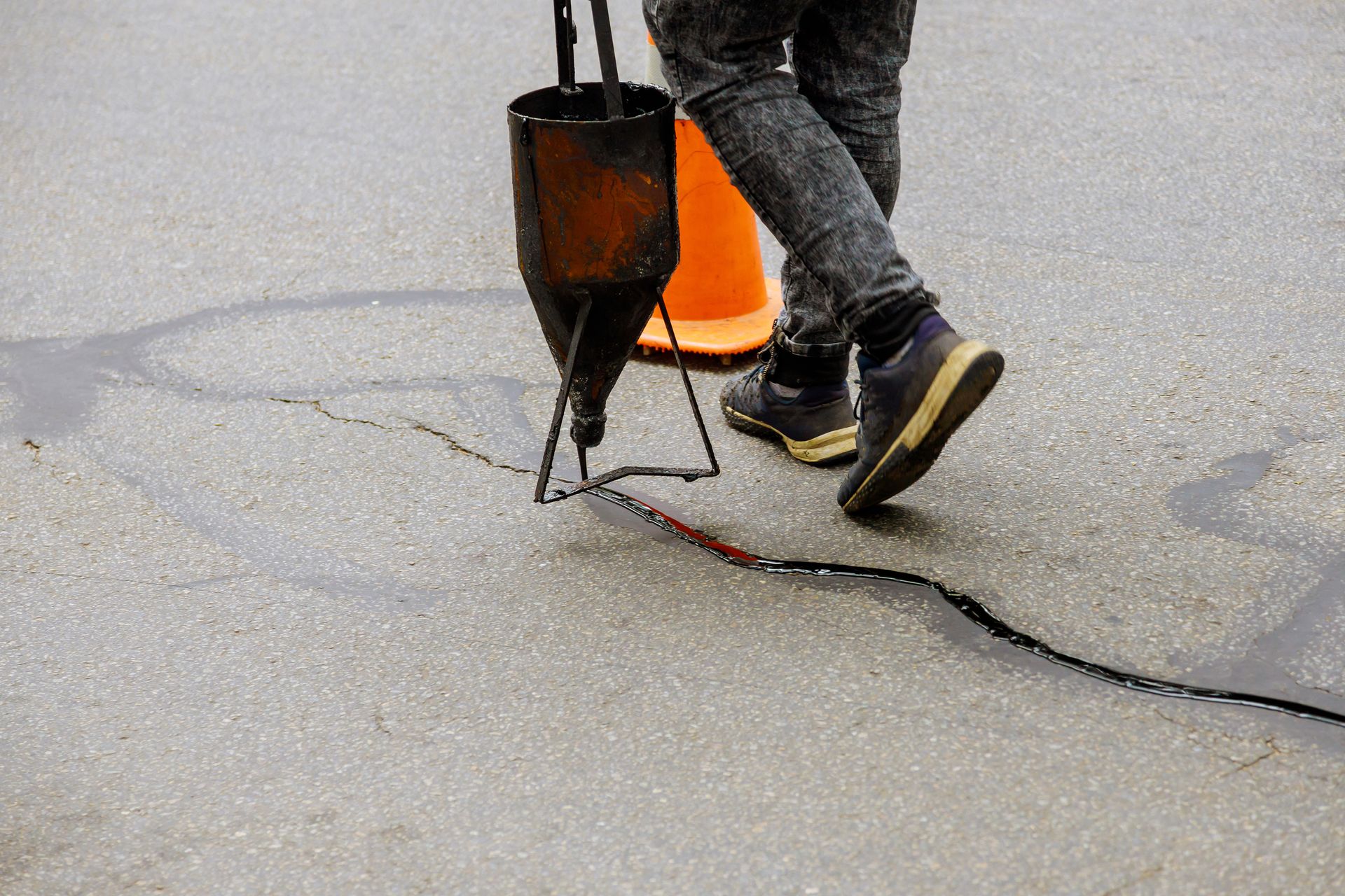 Worker using a jackhammer to break cracked pavement on a road Worker using a jackhammer to break cracked pavement on a road