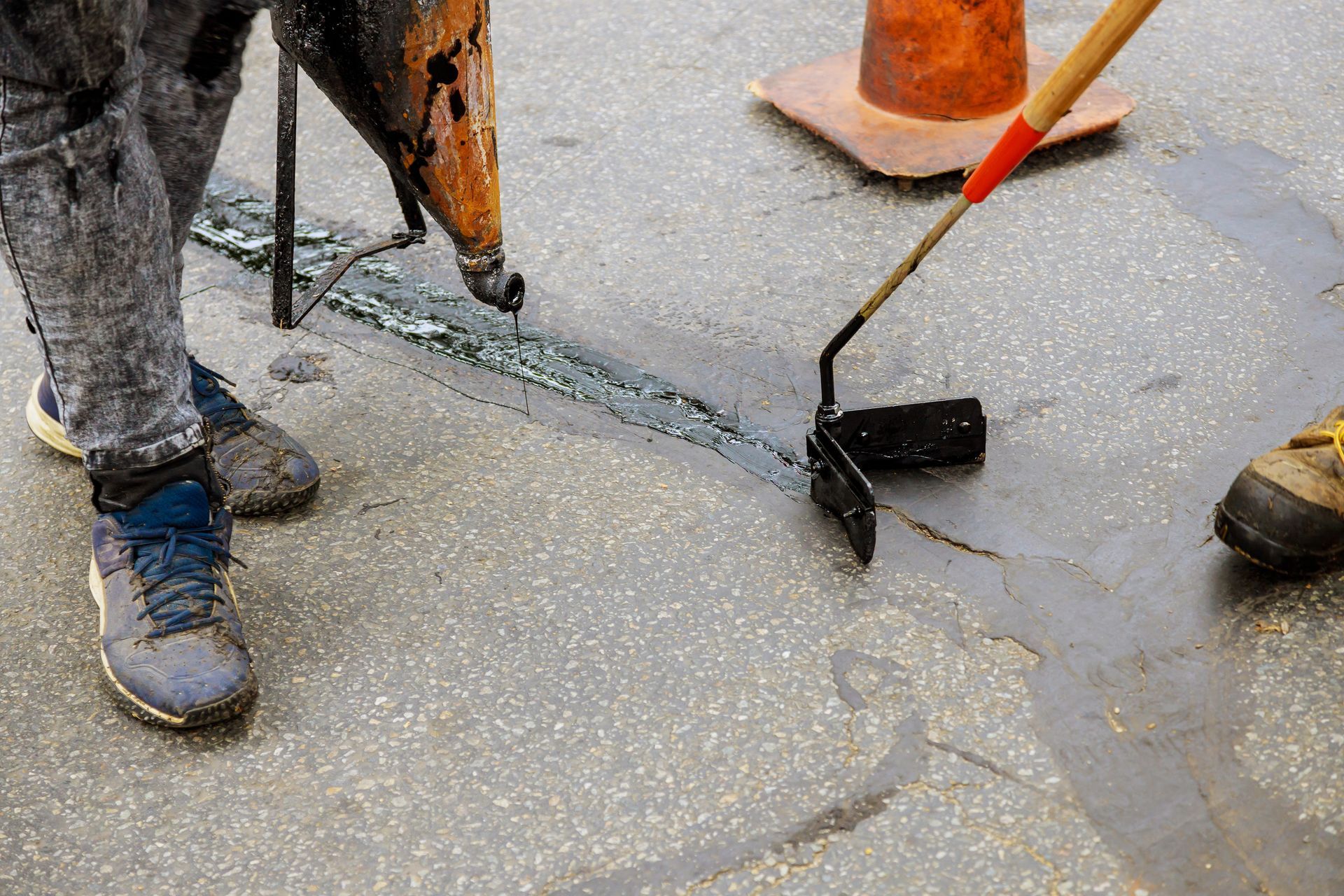 Workers smoothing wet concrete with a trowel around orange traffic cones Workers smoothing wet concrete with a trowel around orange traffic cones