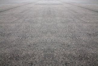 Close-up of a gray asphalt road surface with a rough, textured pattern. Close-up of a gray asphalt road surface with a rough, textured pattern.