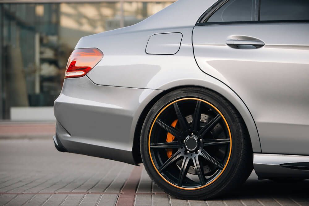 A silver car with black wheels and a yellow rim is parked on a sidewalk — Marx Forster Tyres & Mechanical In Forster, NSW