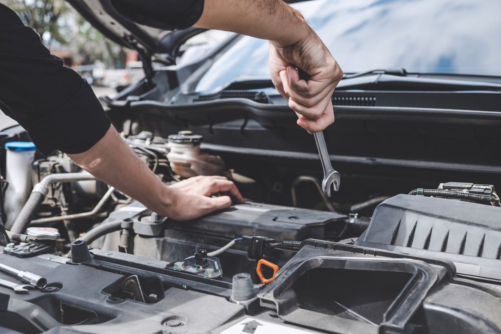 A Man is Working on the Engine of a Car With a Wrench — Marx Forster Tyres & Mechanical In Forster, NSW