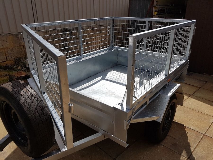 A trailer with a cage on top of it is parked on a sidewalk — Marx Forster Tyres & Mechanical In Forster, NSW