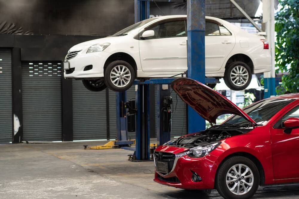 Two cars are sitting on a lift in a garage — Marx Forster Tyres & Mechanical In Forster, NSW