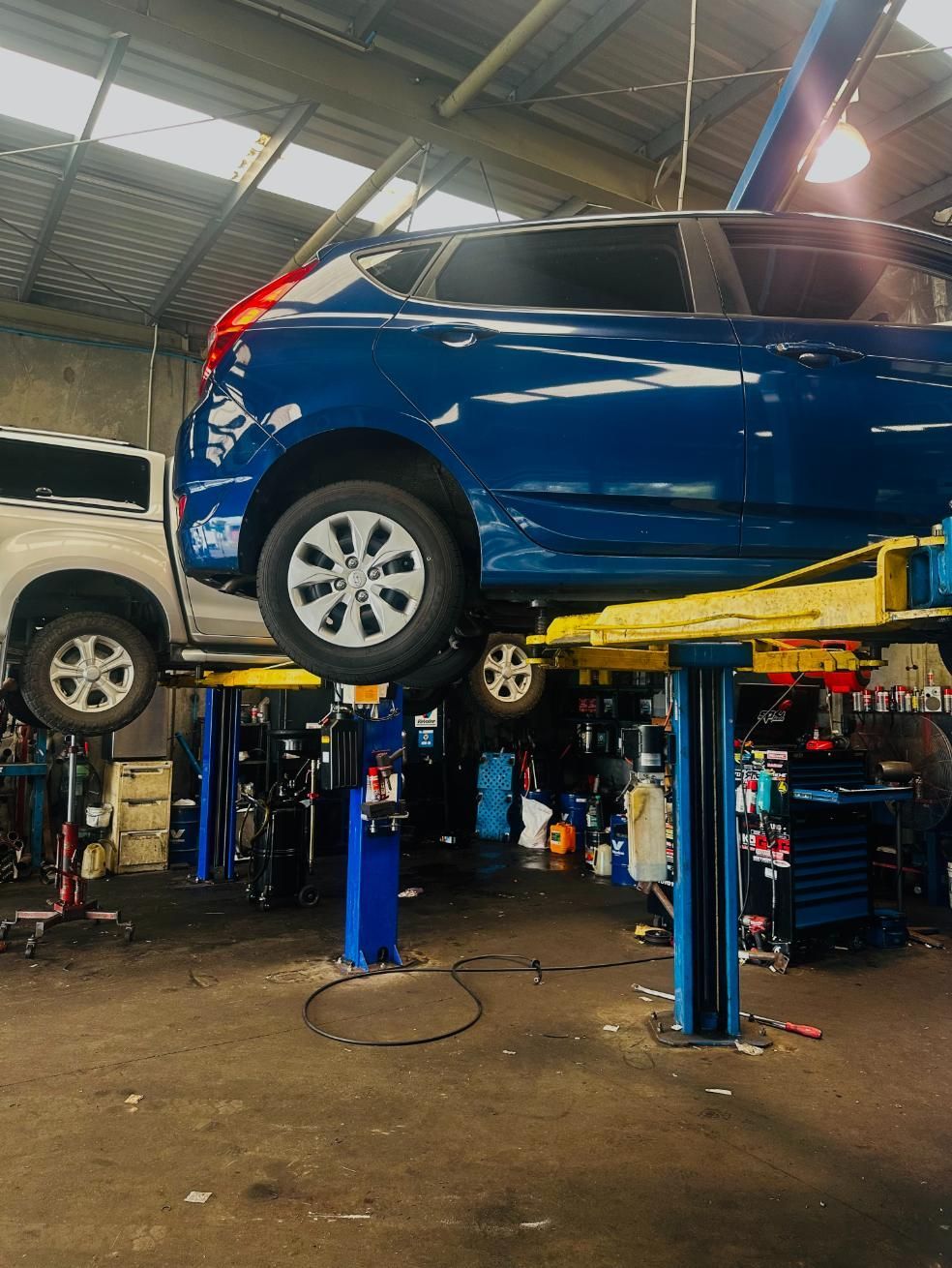 A Blue Car is on a Lift in a Garage — Marx Forster Tyres & Mechanical In Forster, NSW