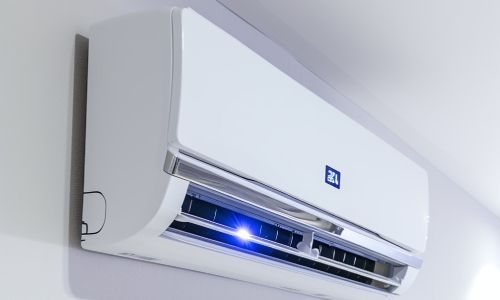 A white air conditioner is hanging on a white wall.