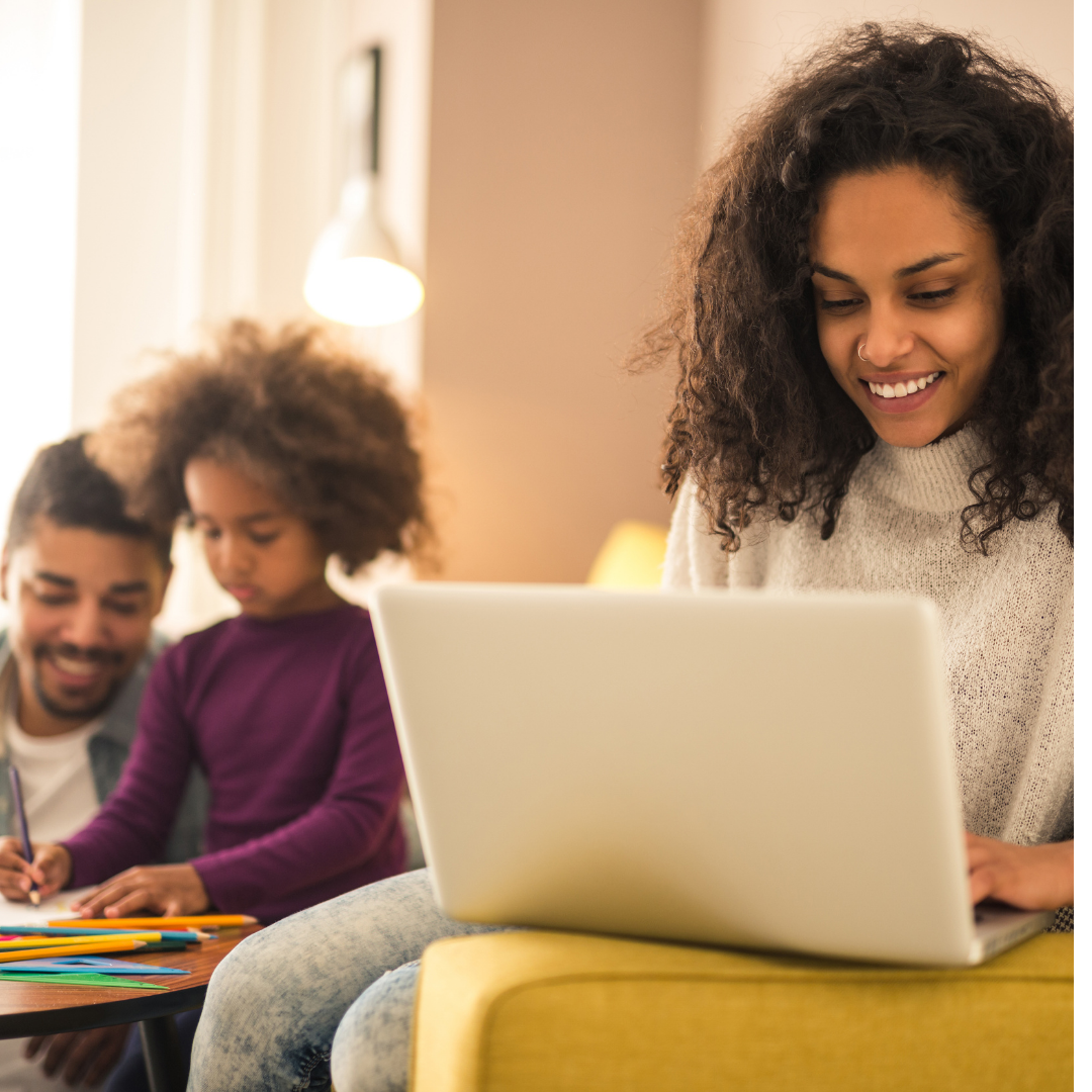 A woman is sitting on a yellow couch using a laptop computer.