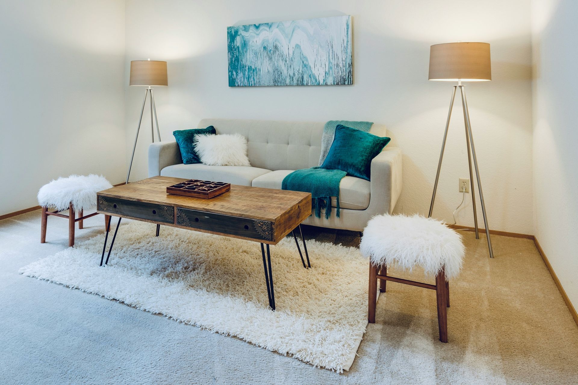 A living room with a couch , coffee table , stools and lamps.