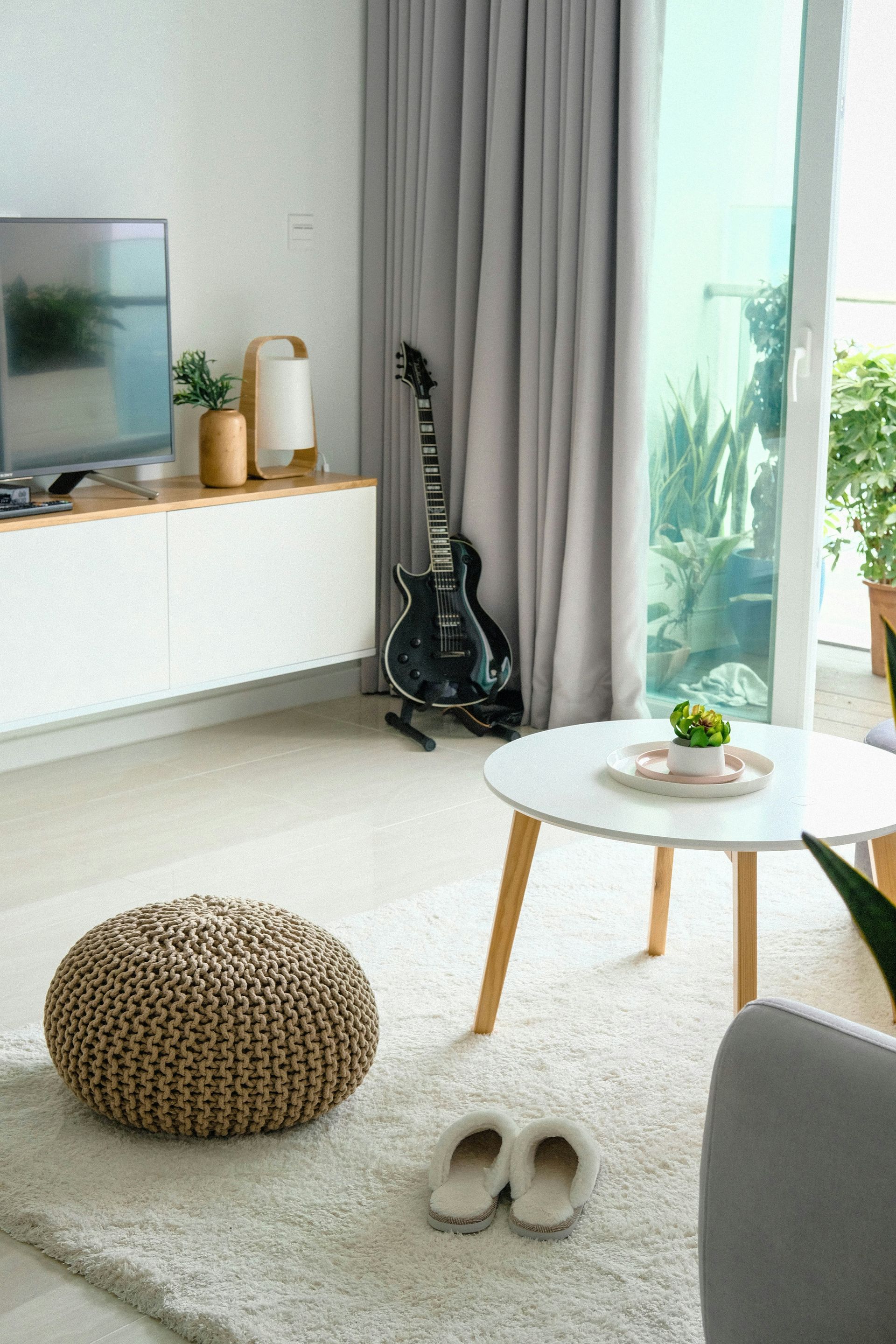 A living room with a guitar on the wall and a table.