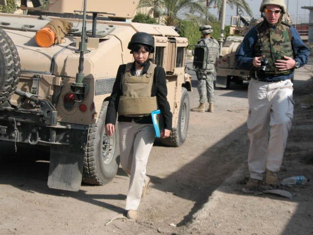 A woman walking in front of a military vehicle