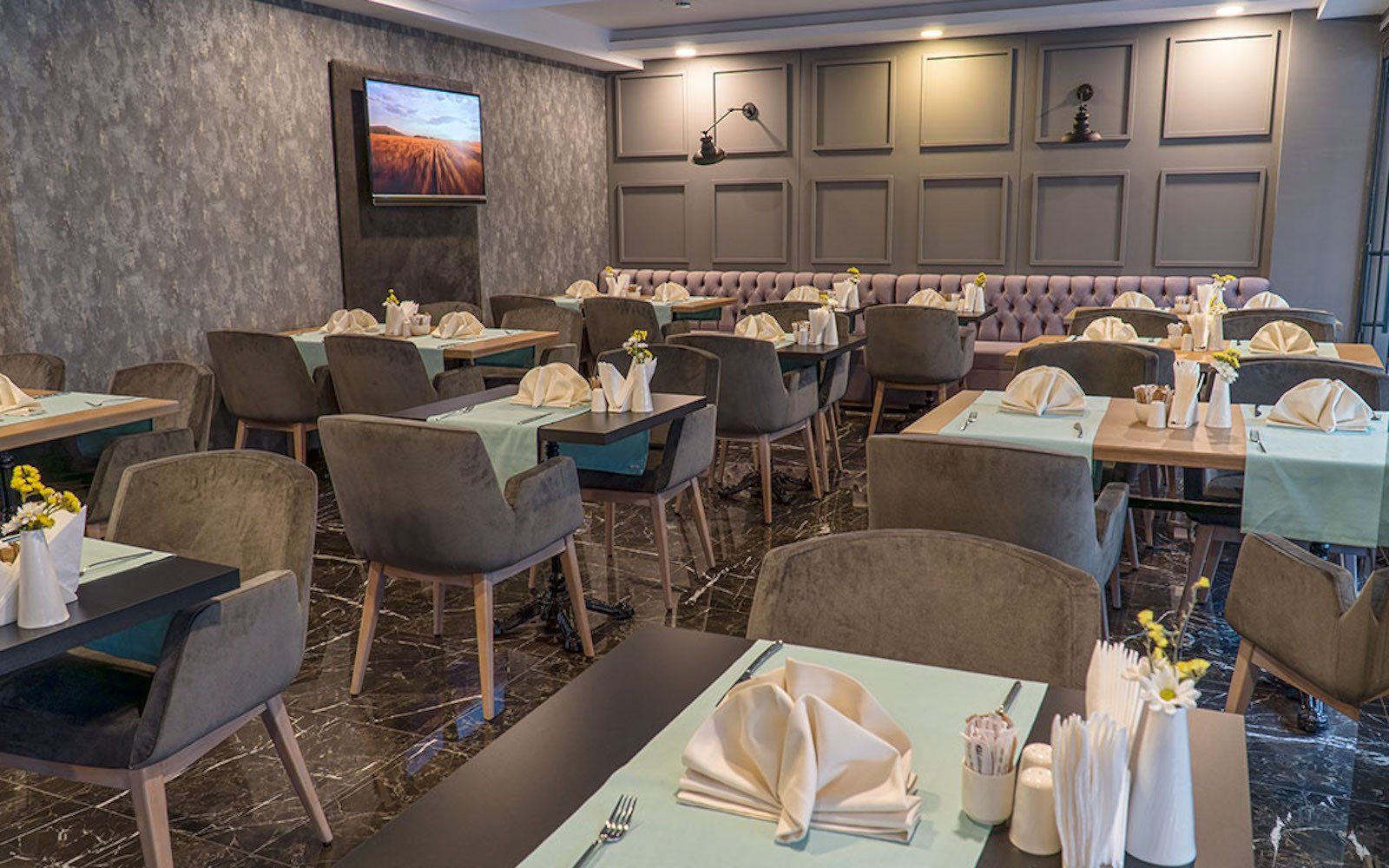 A restaurant with tables and chairs and a television on the wall.