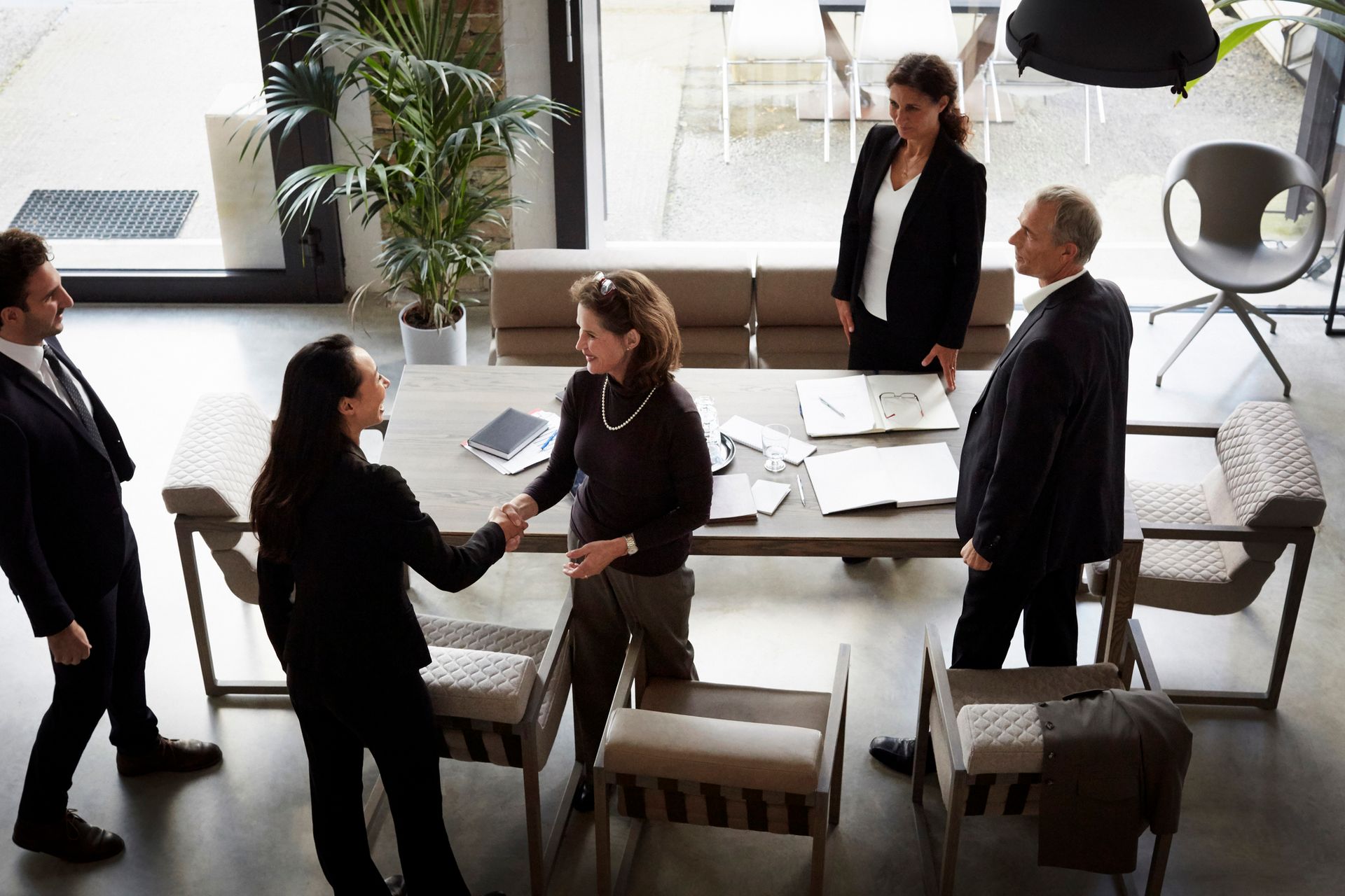 Business people shaking hands around a table in an office setting.