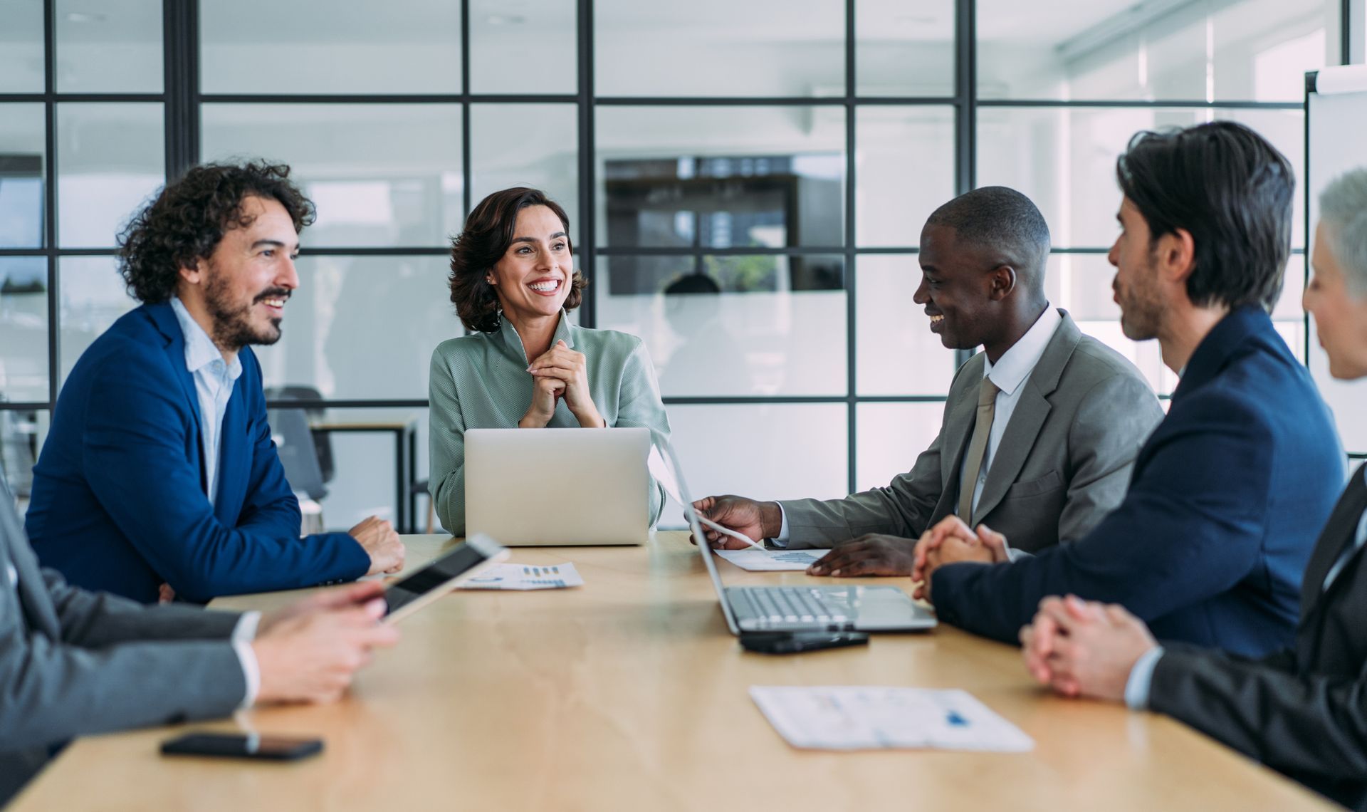 Business team in a meeting, gathered around a table, smiling and discussing.