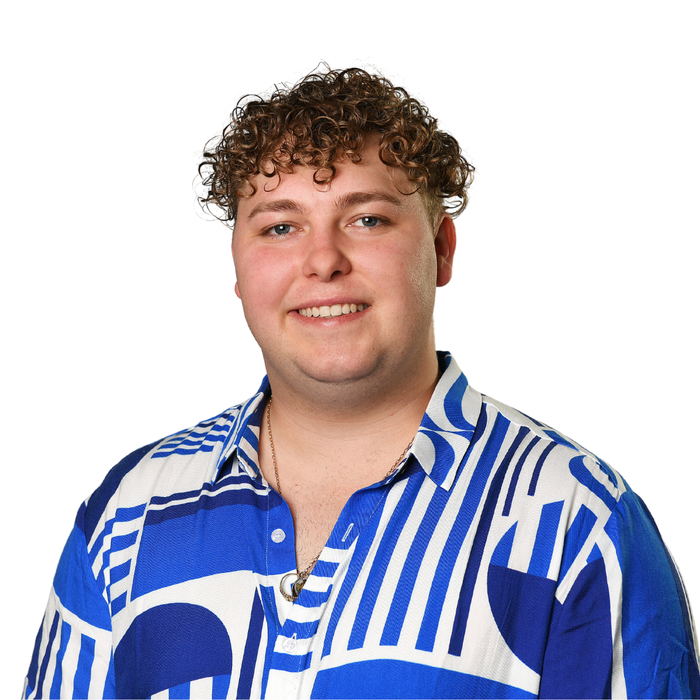 A young man with curly hair is wearing a blue and white shirt.