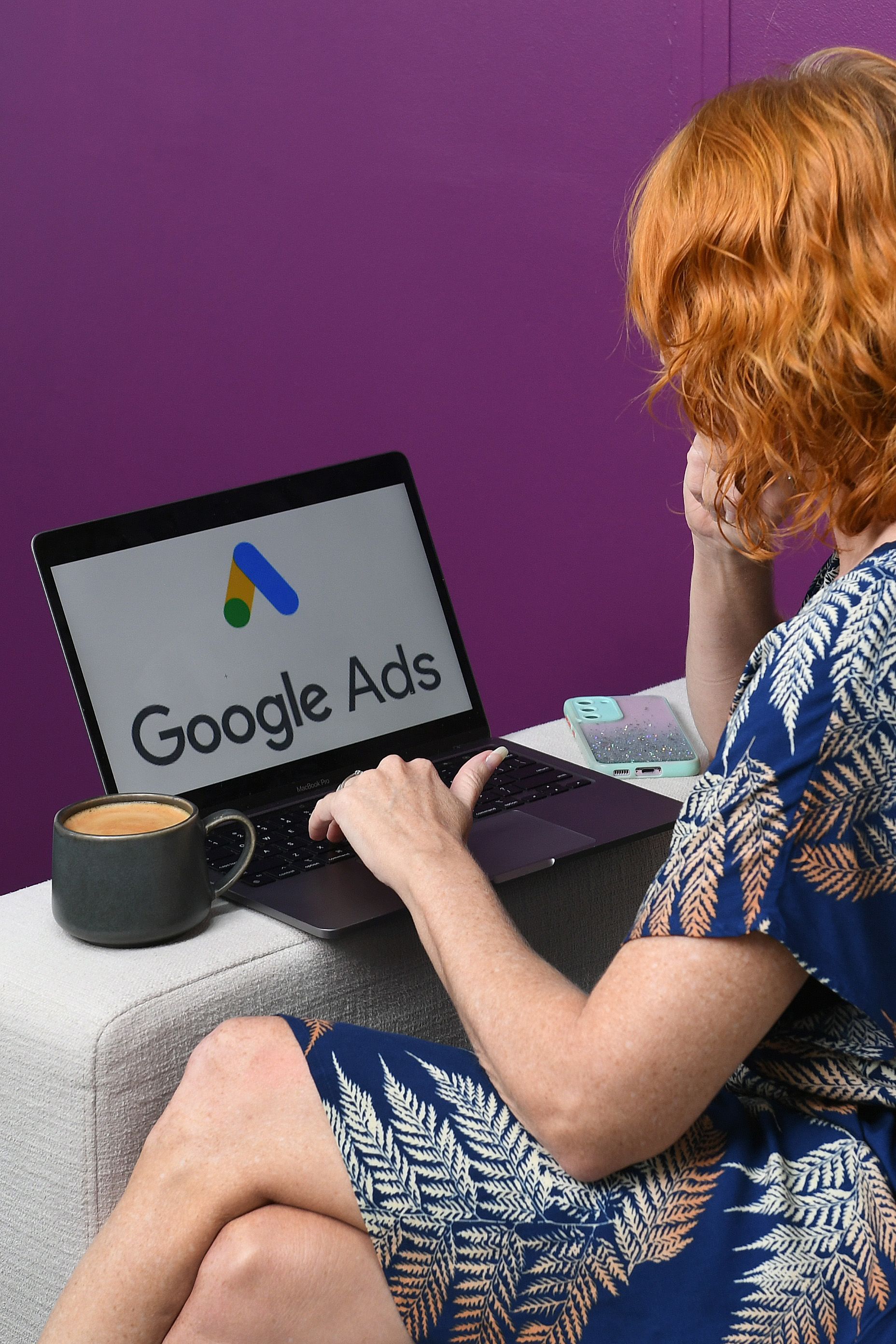 A woman is sitting on a couch using a laptop computer.