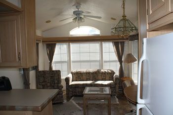 Interior of a small living area with furniture, windows, and ceiling fan.