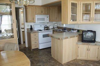 Kitchen with light wood cabinets, white appliances, and a small television.