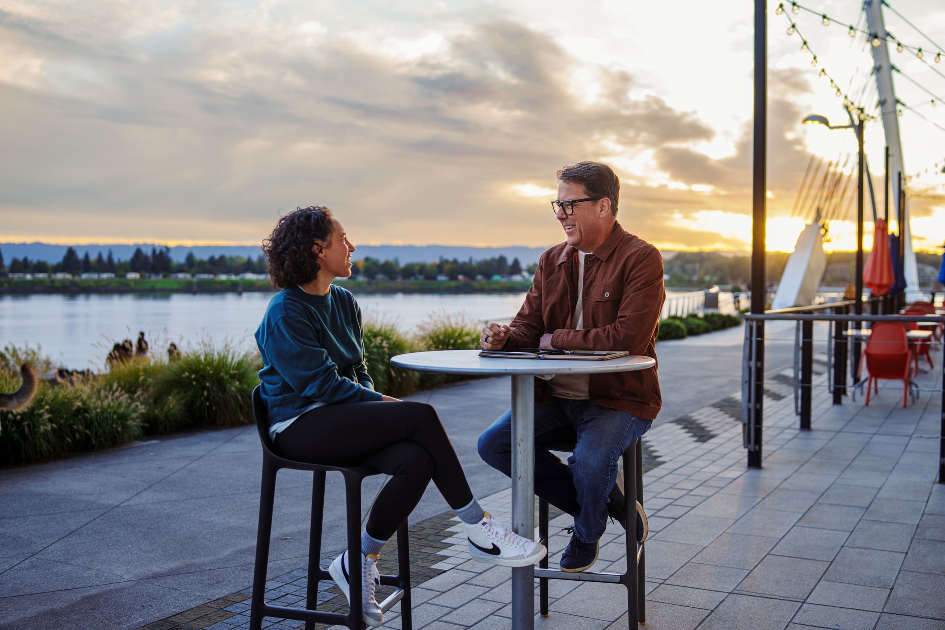 A man and a woman are sitting at a table talking to each other.