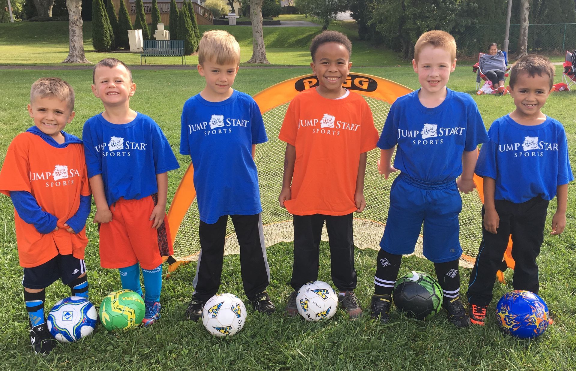 A group of young boys are posing for a picture with soccer balls.