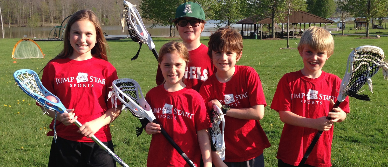 A group of young people are holding lacrosse sticks in a field.