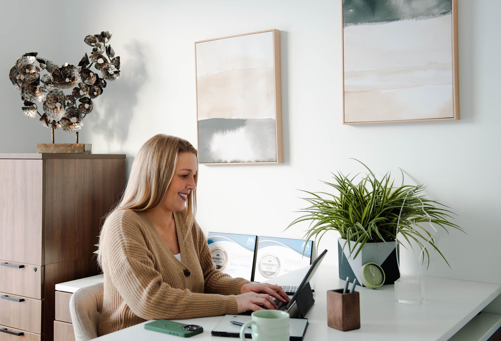 A woman is sitting at a desk using a laptop computer.