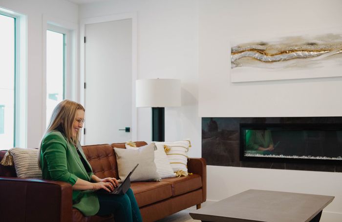A woman is sitting on a couch using a laptop computer.