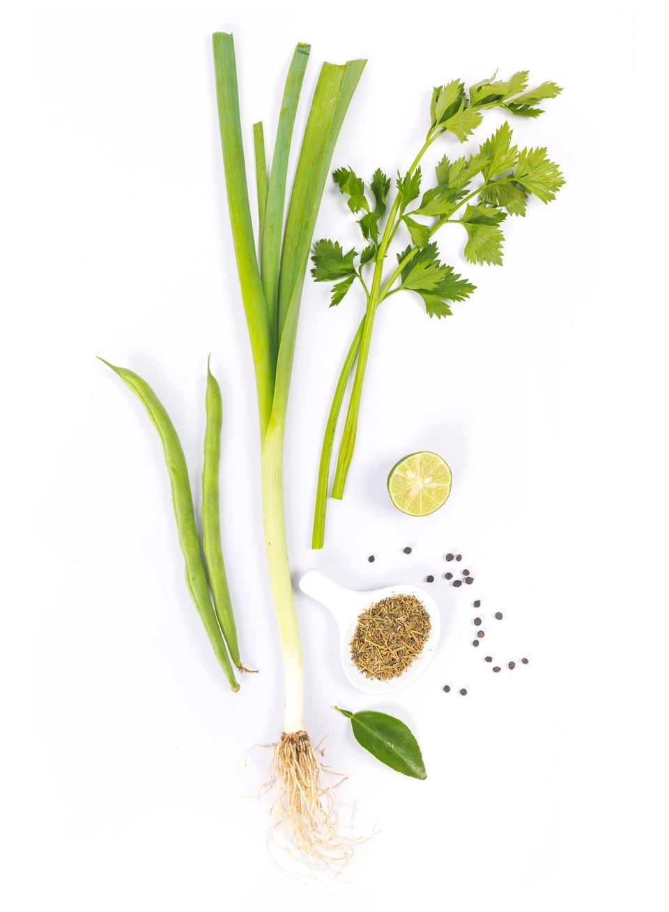 Un mazzo di verdure verdi e spezie su uno sfondo bianco.