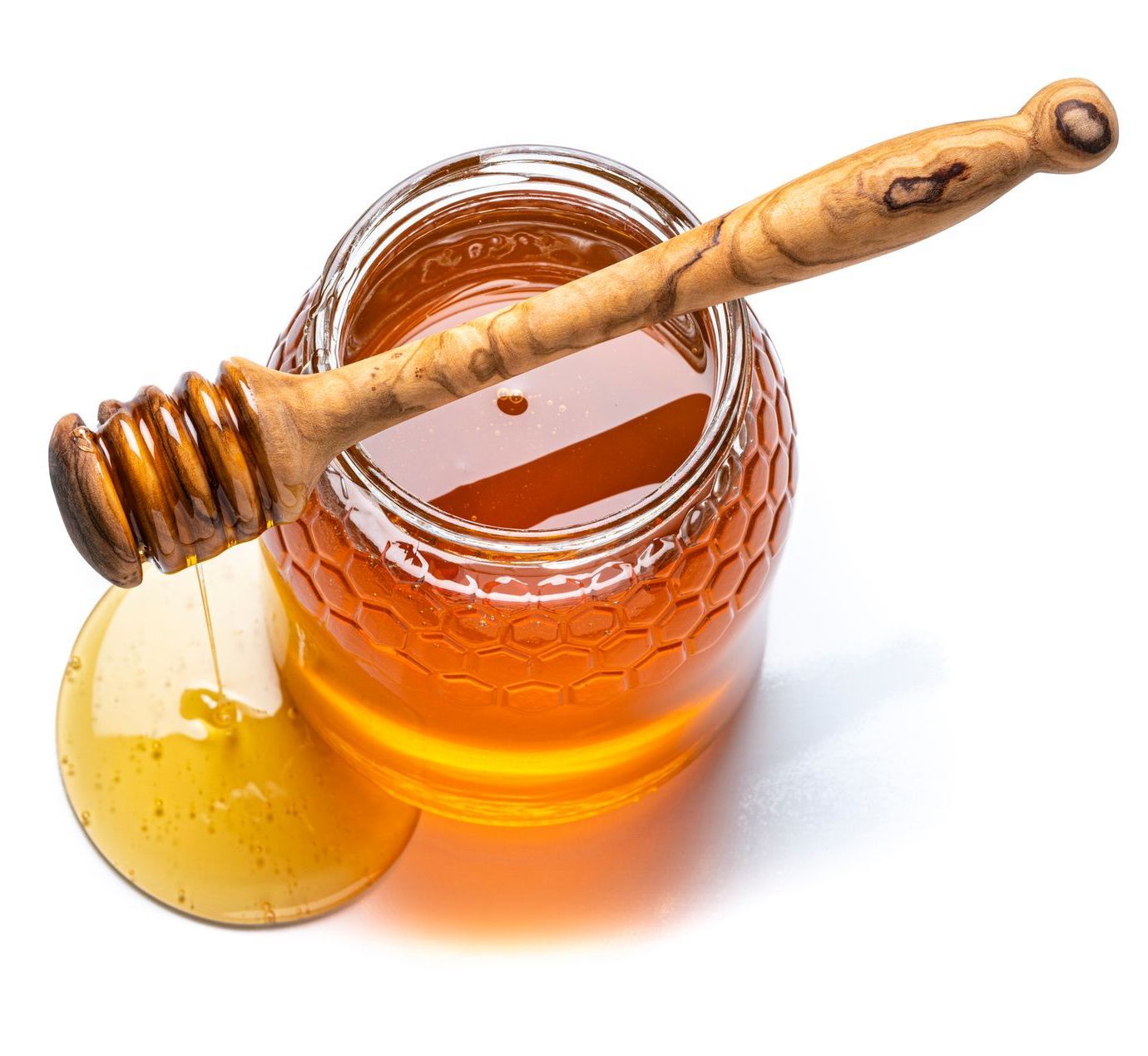 Un barattolo di miele con dentro un mestolo di legno.