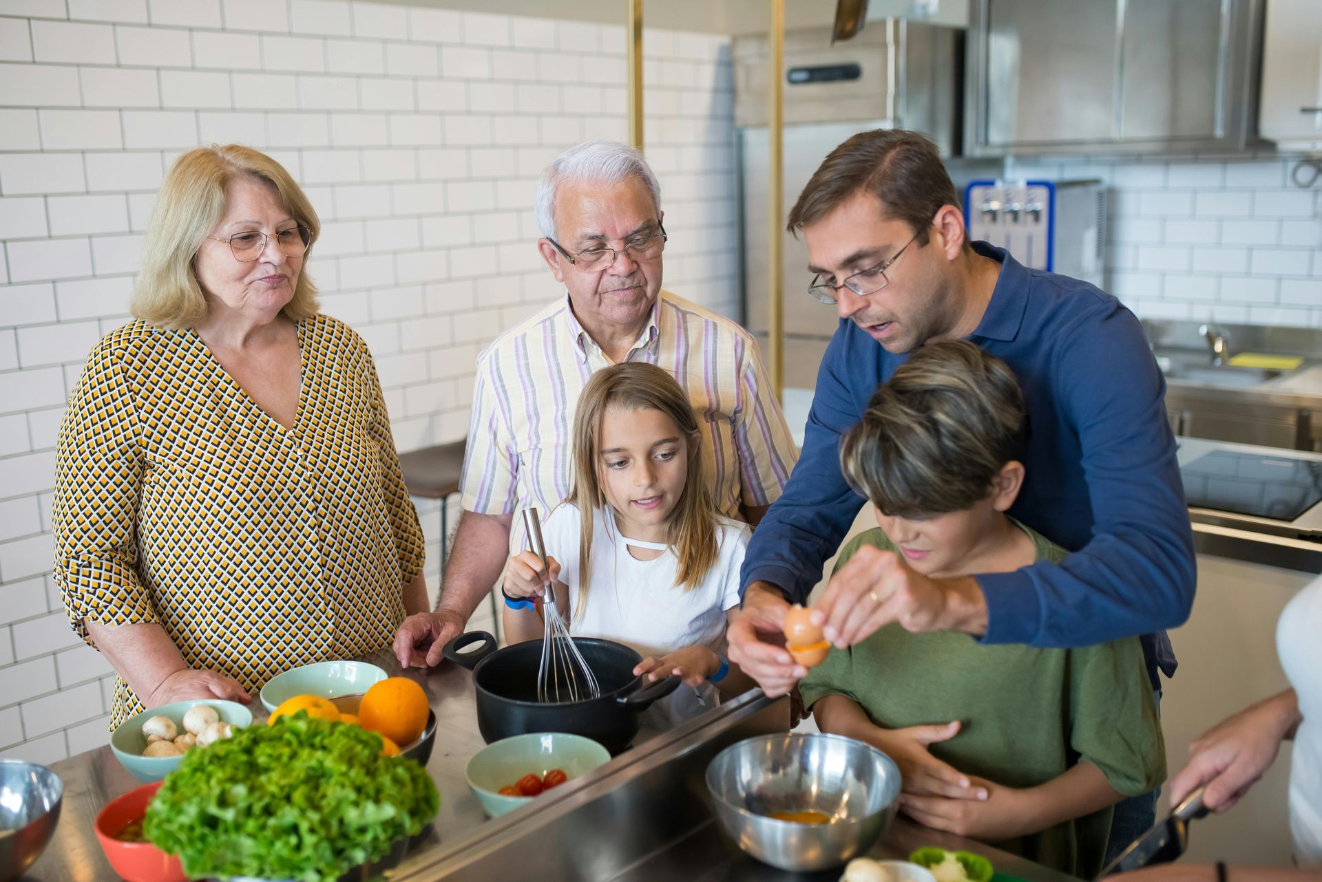 Family cooking together in a bright kitchen, preparing food around a counter with vegetables and bowls